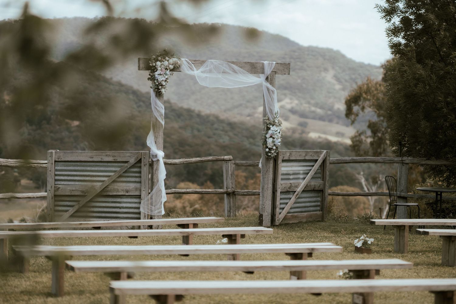 A panoramic view of wooden pole fences stretching across rugged mountain terrain under a cloudy sky at Howqua Lodge