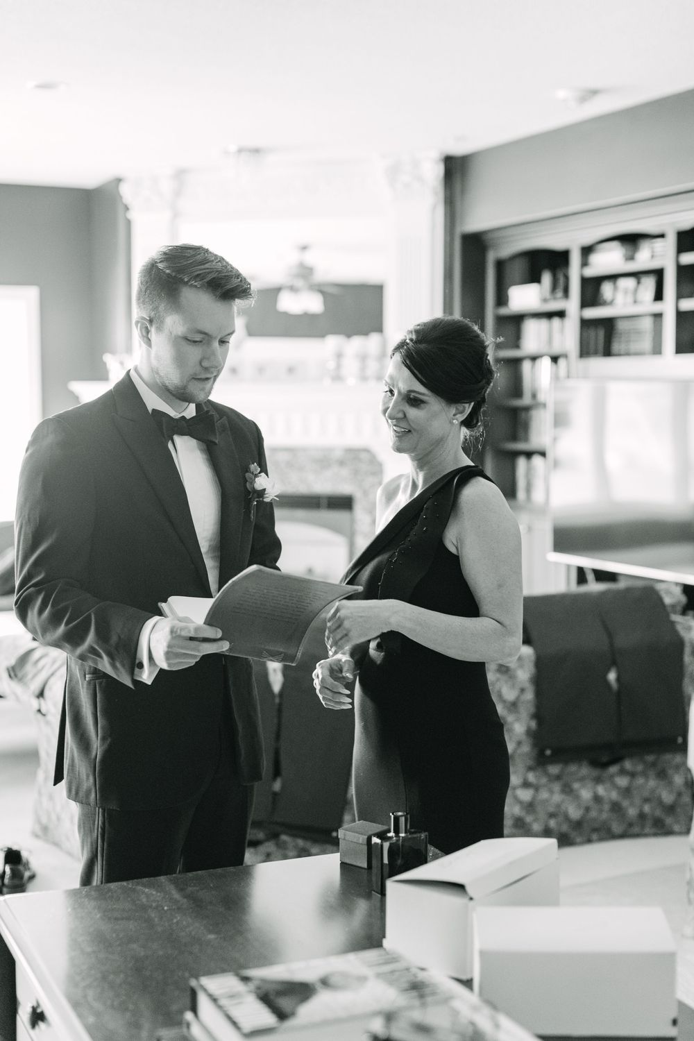 Sweet photo of groom Carter and his mother chatting about a family piece during getting ready portraits