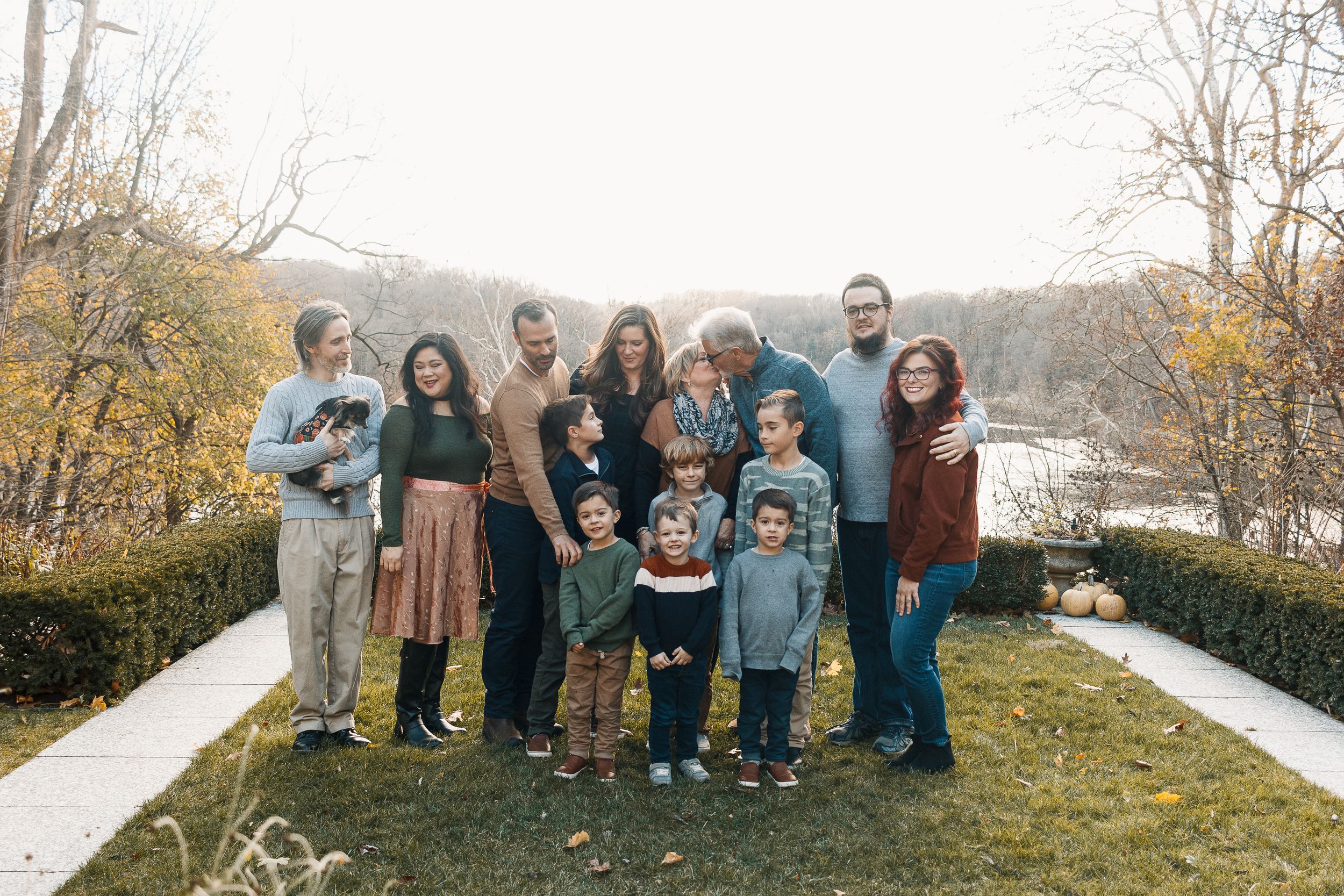 A group of people standing together outdoors on an autumn day with mountains and a lake in the background.