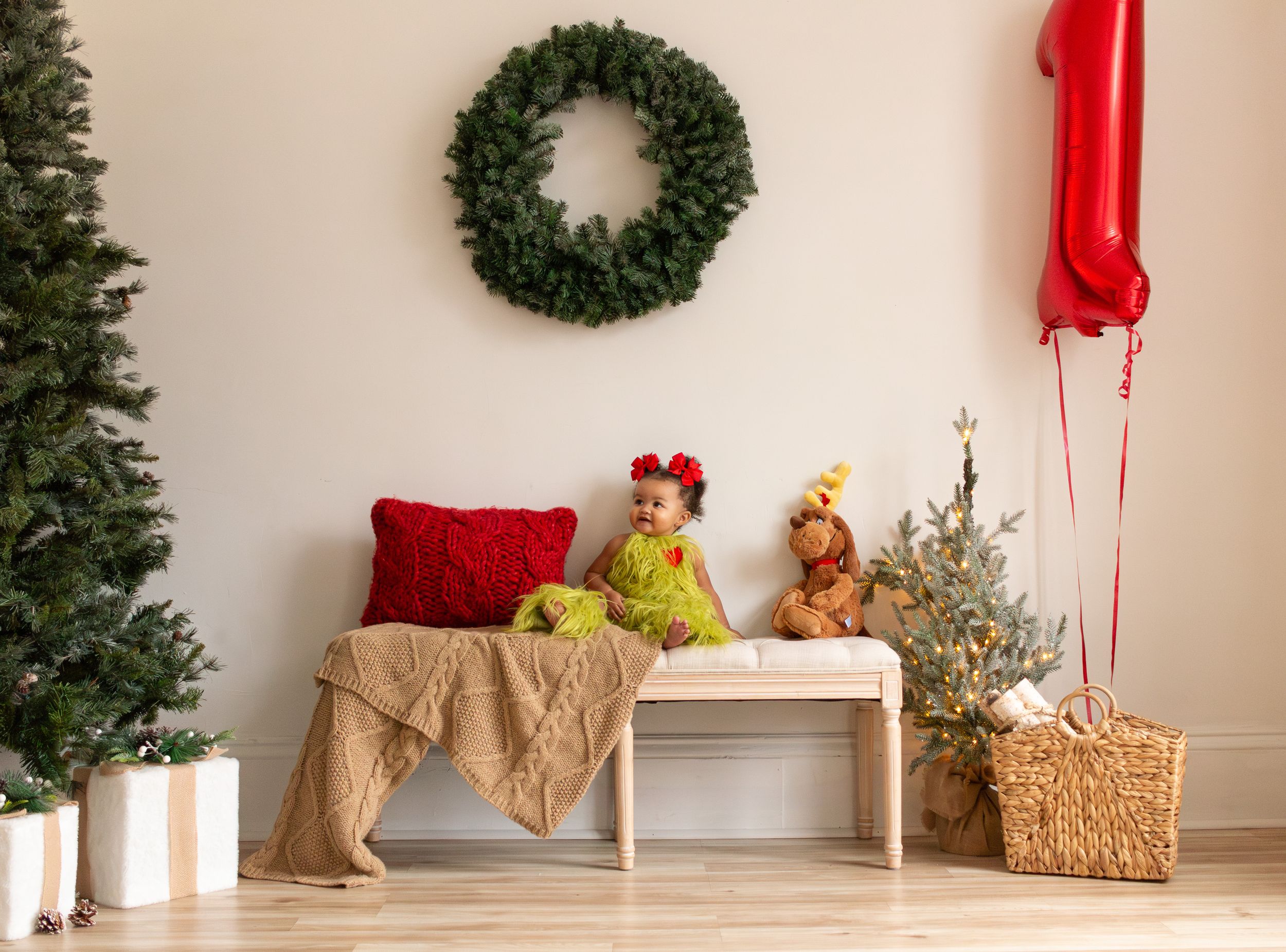 A Christmas-themed living room decorated with a green wreath, red ribbons, and hay bales creates a festive farmhouse setting.