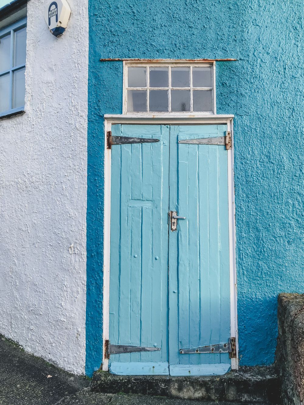 A series of weathered turquoise blue doors arranged horizontally against white and teal painted walls.