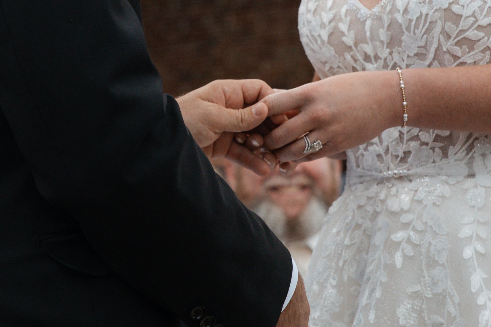 Close-up photo of a bride and groom exchanging rings during a wedding ceremony.