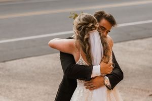 A couple in formal attire shares an intimate moment while dancing together on a street.
