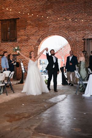 Wedding celebration inside rustic brick venue with string lights and archway entrance.