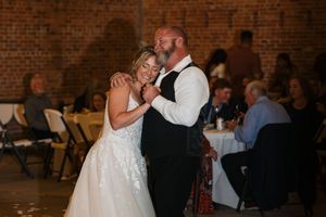 Wedding ceremony in a rustic brick venue with guests seated in rows watching the couple exchange vows.
