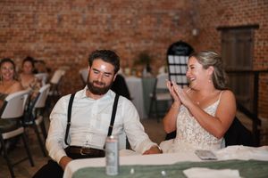 A candid reception moment showing laughter and celebration inside a rustic brick venue.
