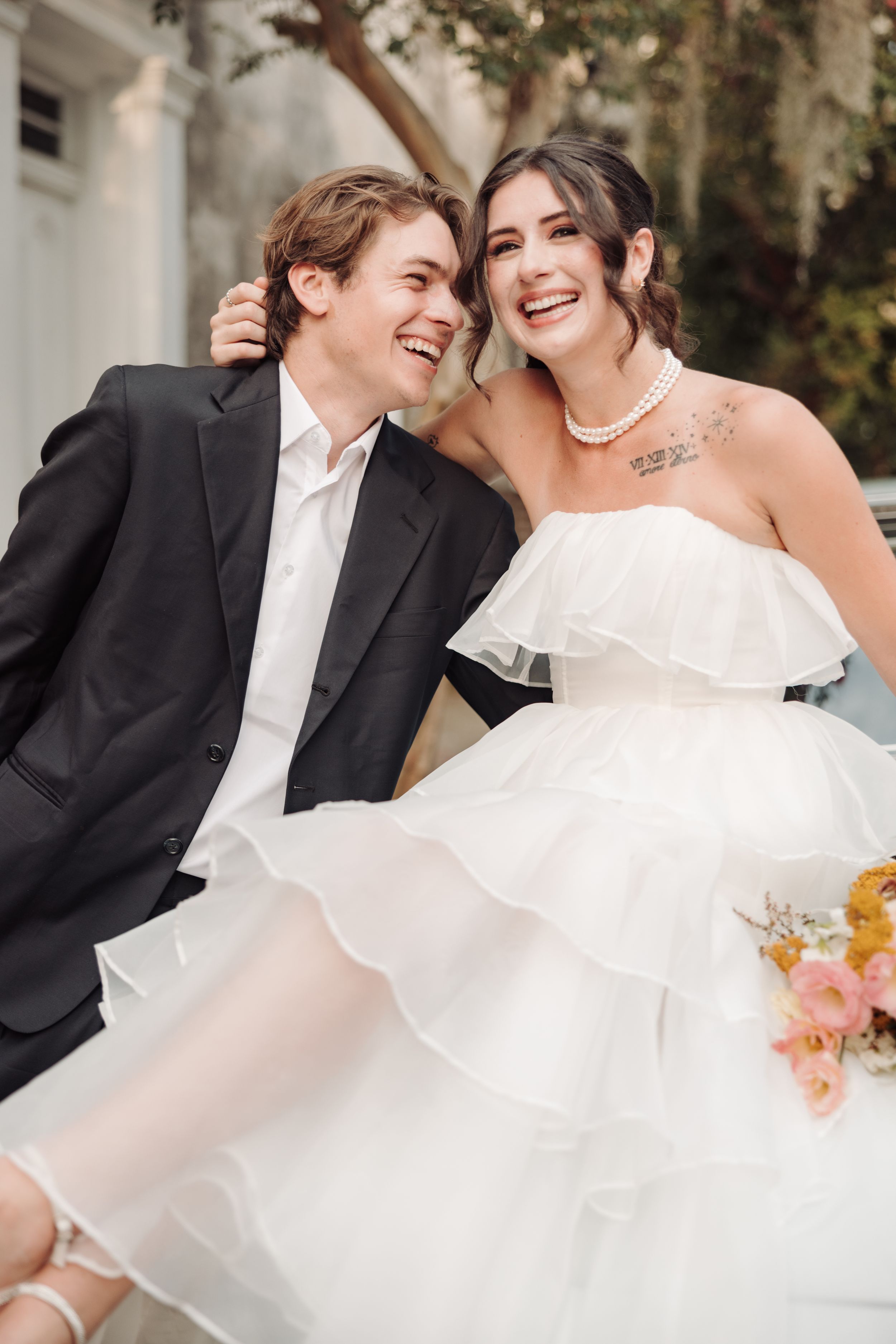 Dancing couple in elegant wedding attire share joyful moments during an outdoor celebration.