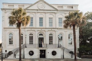 Historic white government building with classical architecture and palm trees along its facade in Charleston, South Carolina.