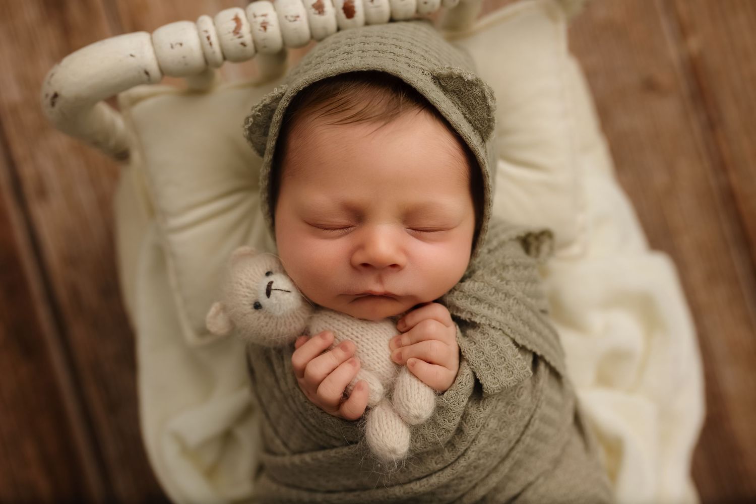 Charlottesville newborn, baby, and family photographer captures baby boy in soft green waffle-knit wrap and bear ear hat and holding stuffy.