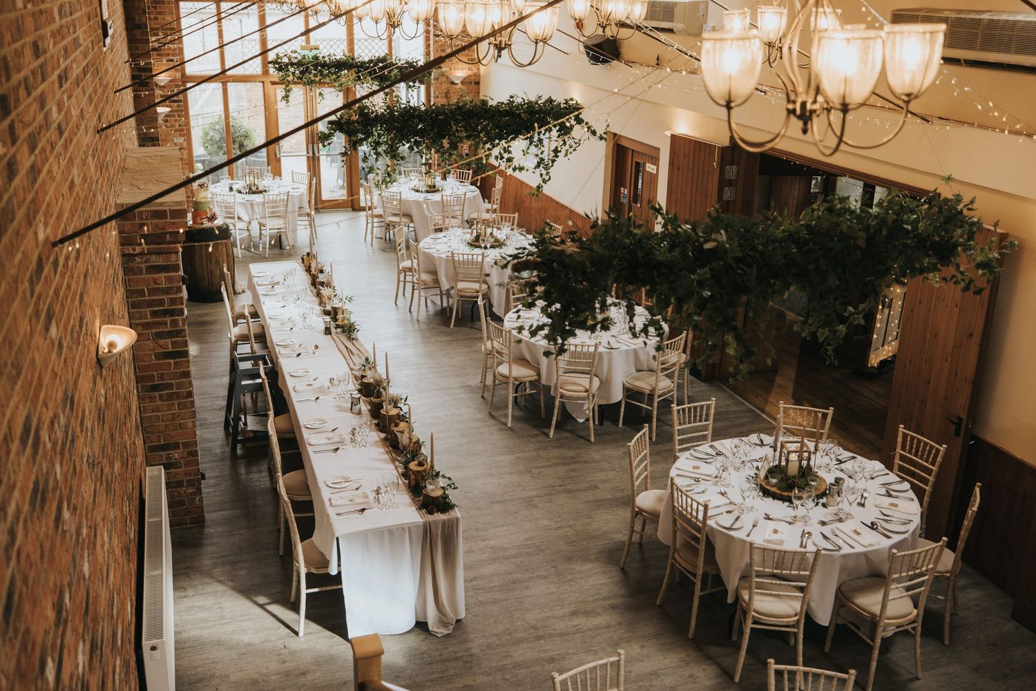 Elegant wedding reception venue with rustic brick walls, round tables, and string lights creating a romantic atmosphere at Hall Farm.