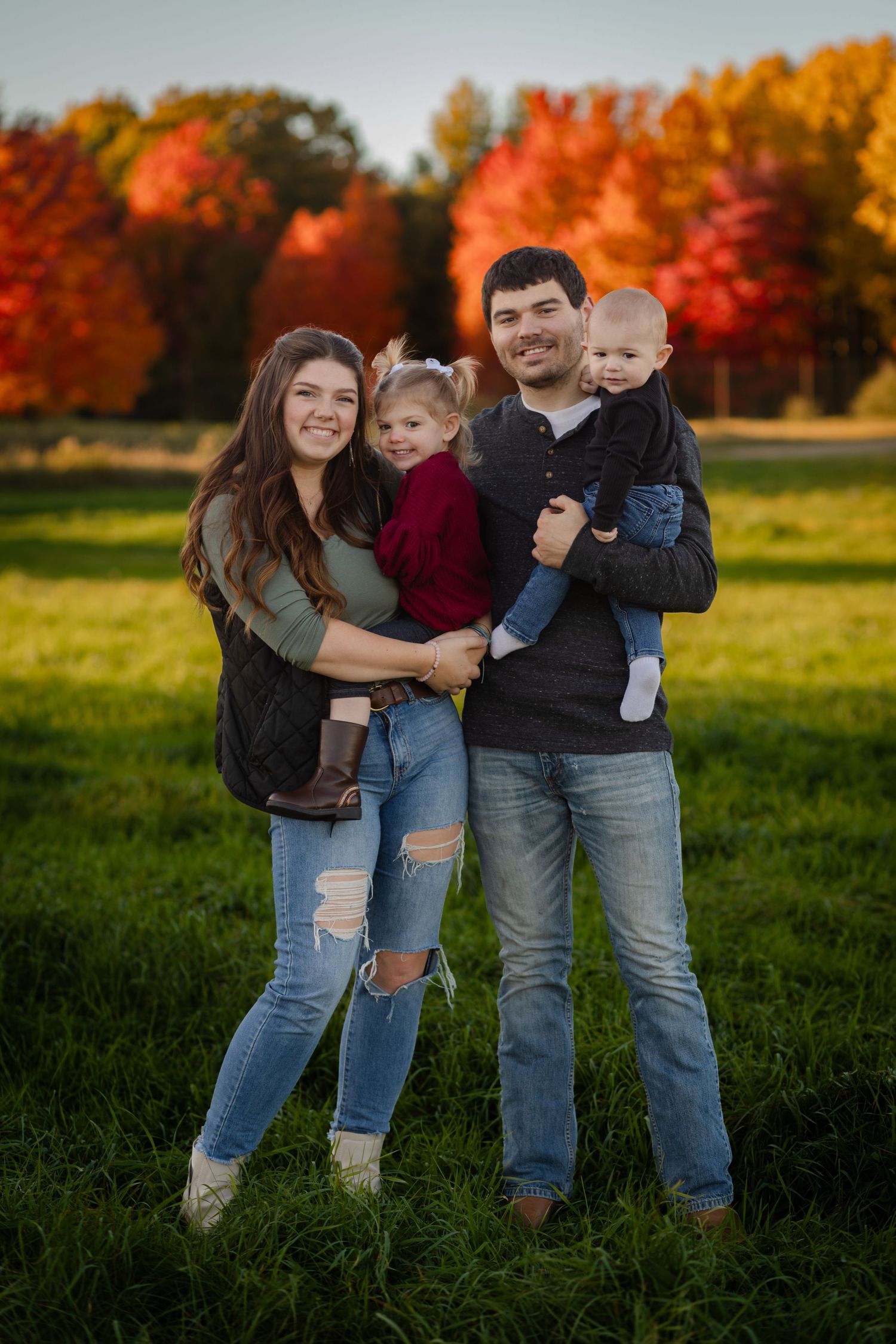 Family of 4 stands in open field in Autumn getting family photos taken. Central Michigan.