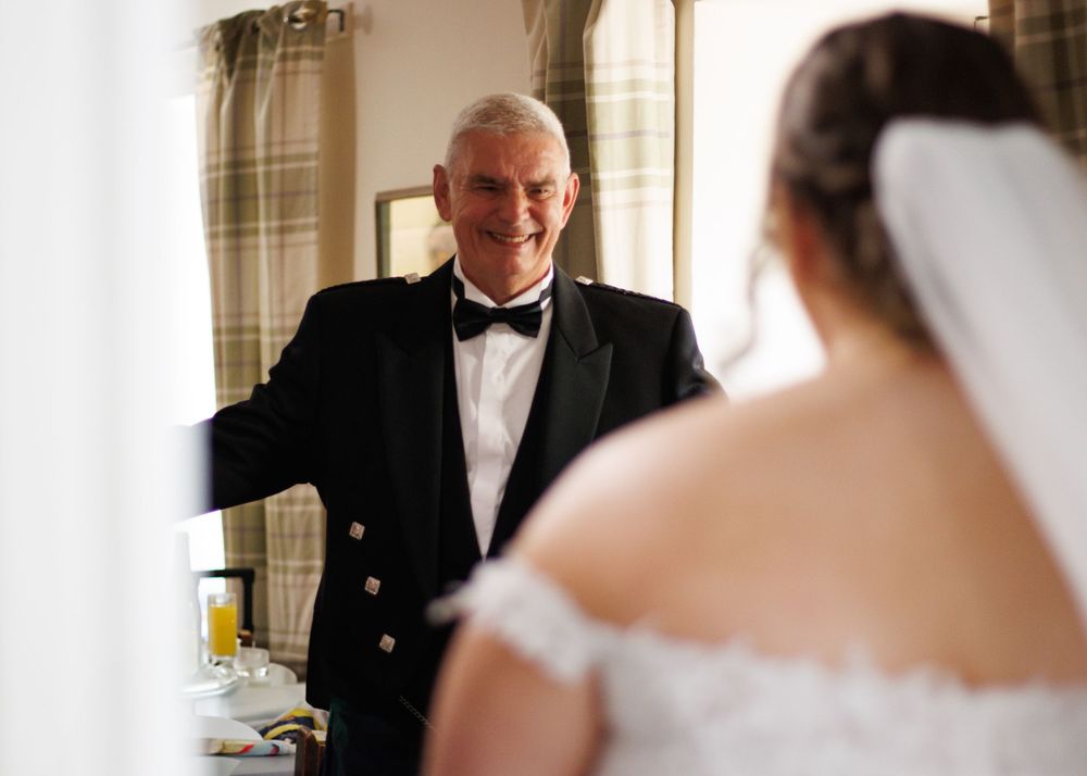 An emotional moment between a father and daughter in formal attire before a wedding ceremony.