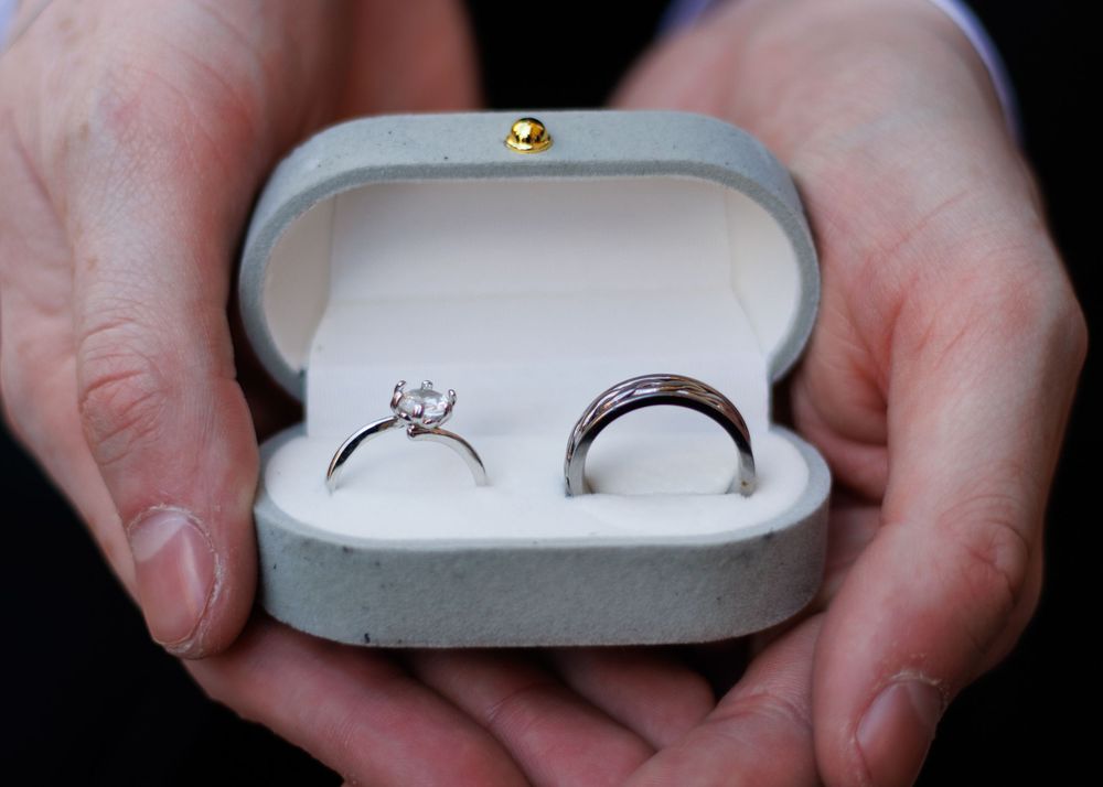 A sequence showing wedding rings being opened in a small white box with hands holding and displaying the jewelry.