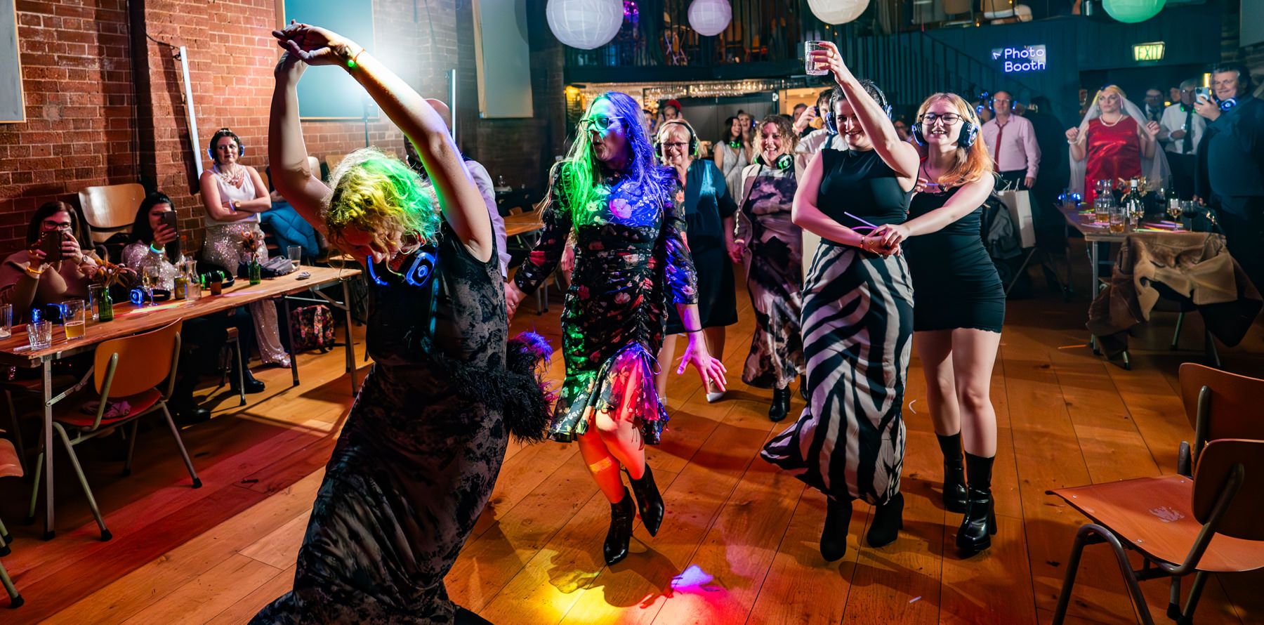 People dancing and enjoying music in a colorful nightclub with disco lights illuminating the dance floor.