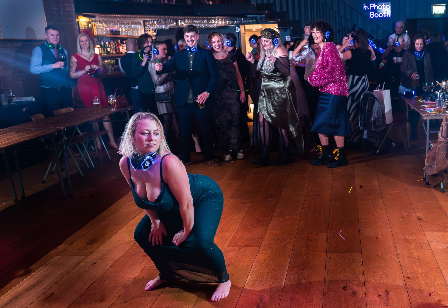 Dancers performing on a wooden dance floor in a dimly lit venue with purple lighting and an audience watching.