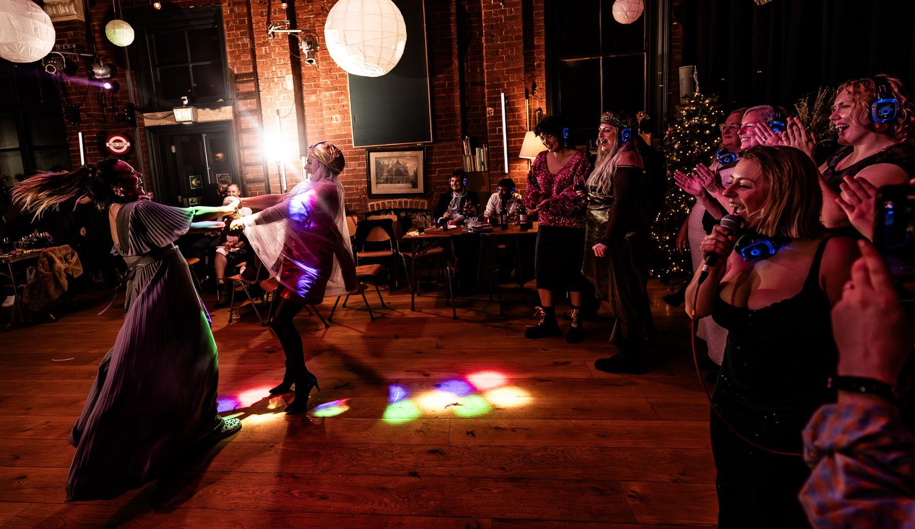 People dancing and socializing at a dimly lit nightclub with glowing lanterns and colorful lighting effects.