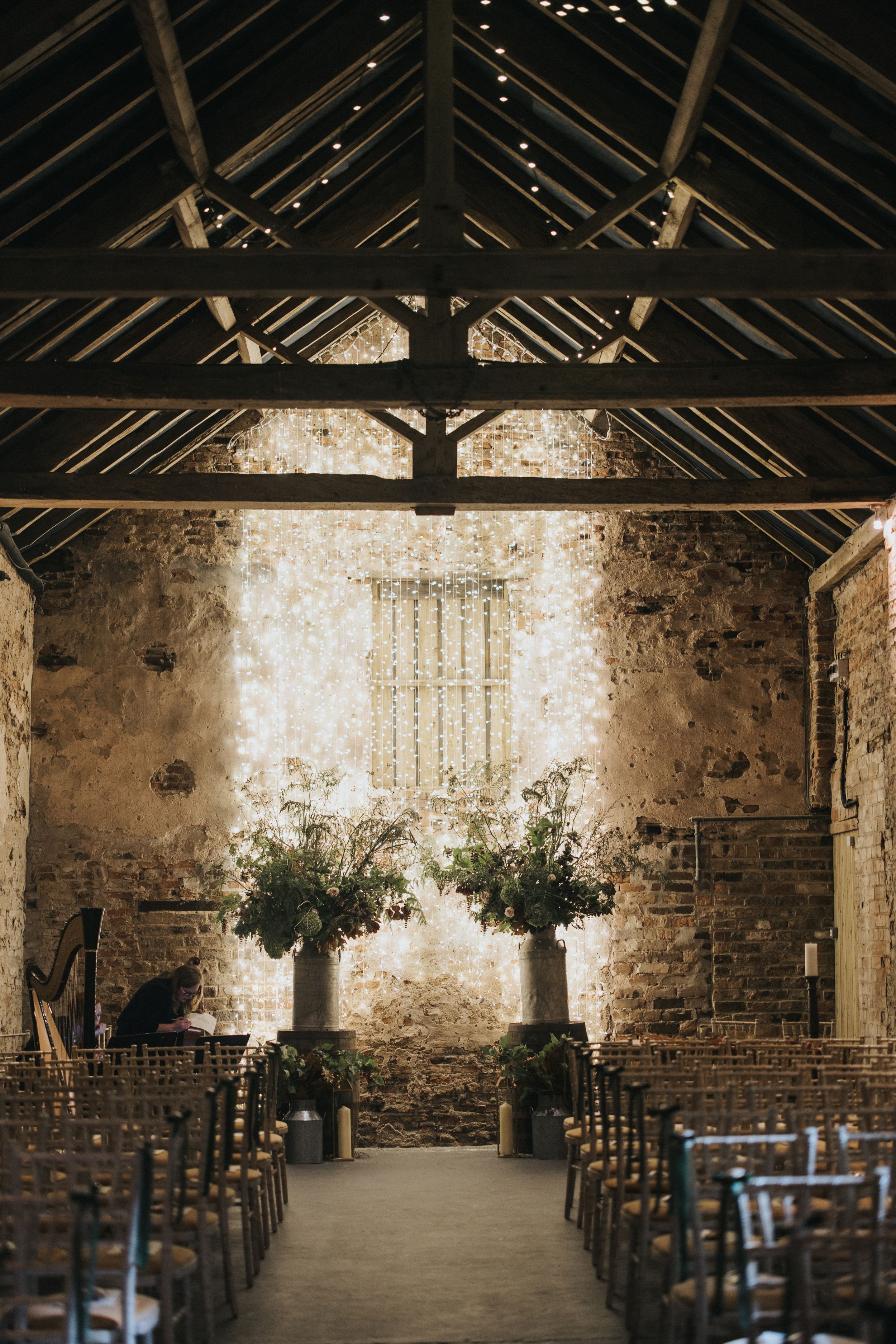 Rustic barn wedding ceremony setup with wooden chairs and exposed stone walls in a historic venue.