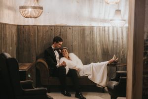 Moody wedding scene inside rustic barn with glowing pendant lights and wooden beams creating intimate ambiance.