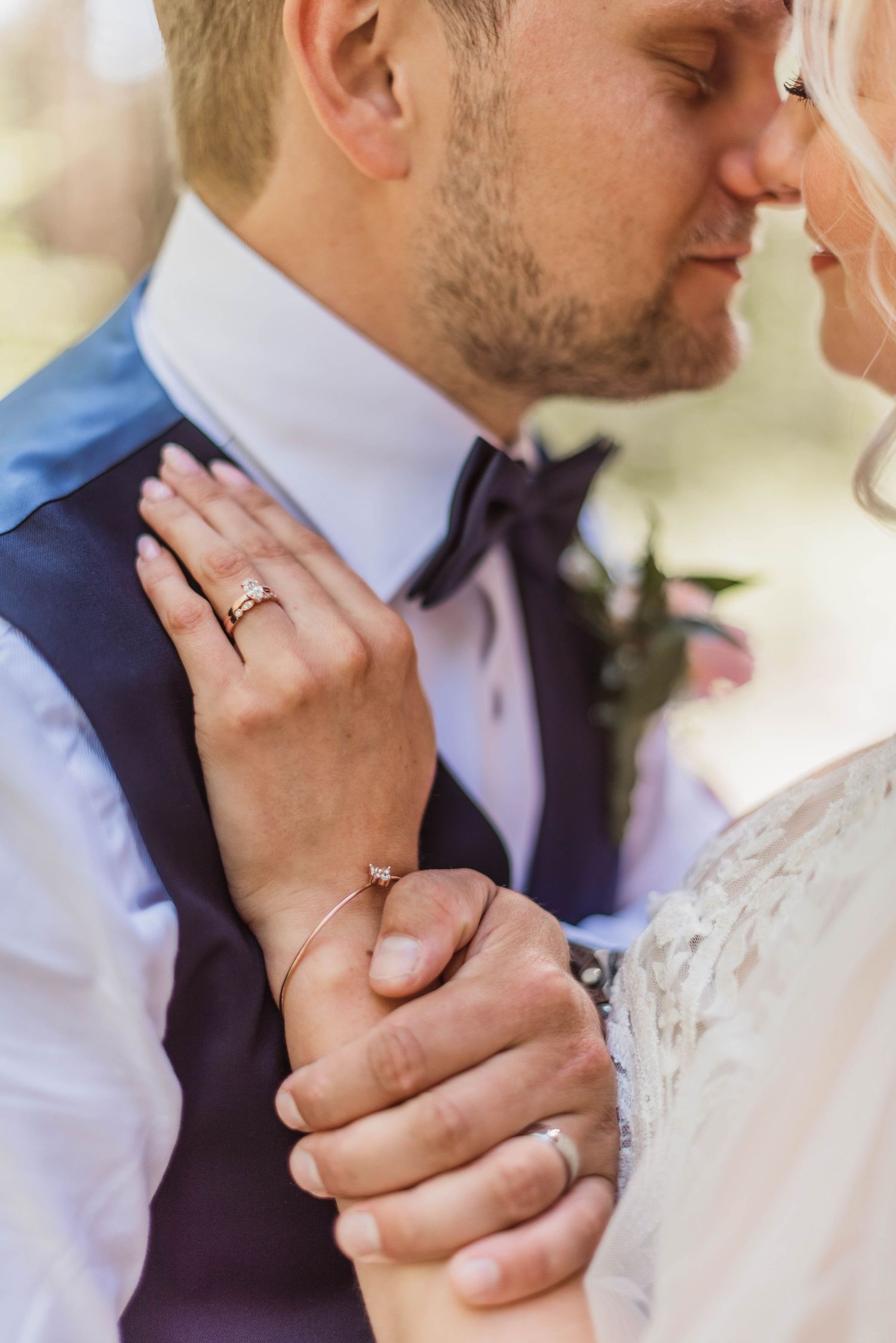 Close up of entwined hands with wedding rings during intimate moment at wedding ceremony.