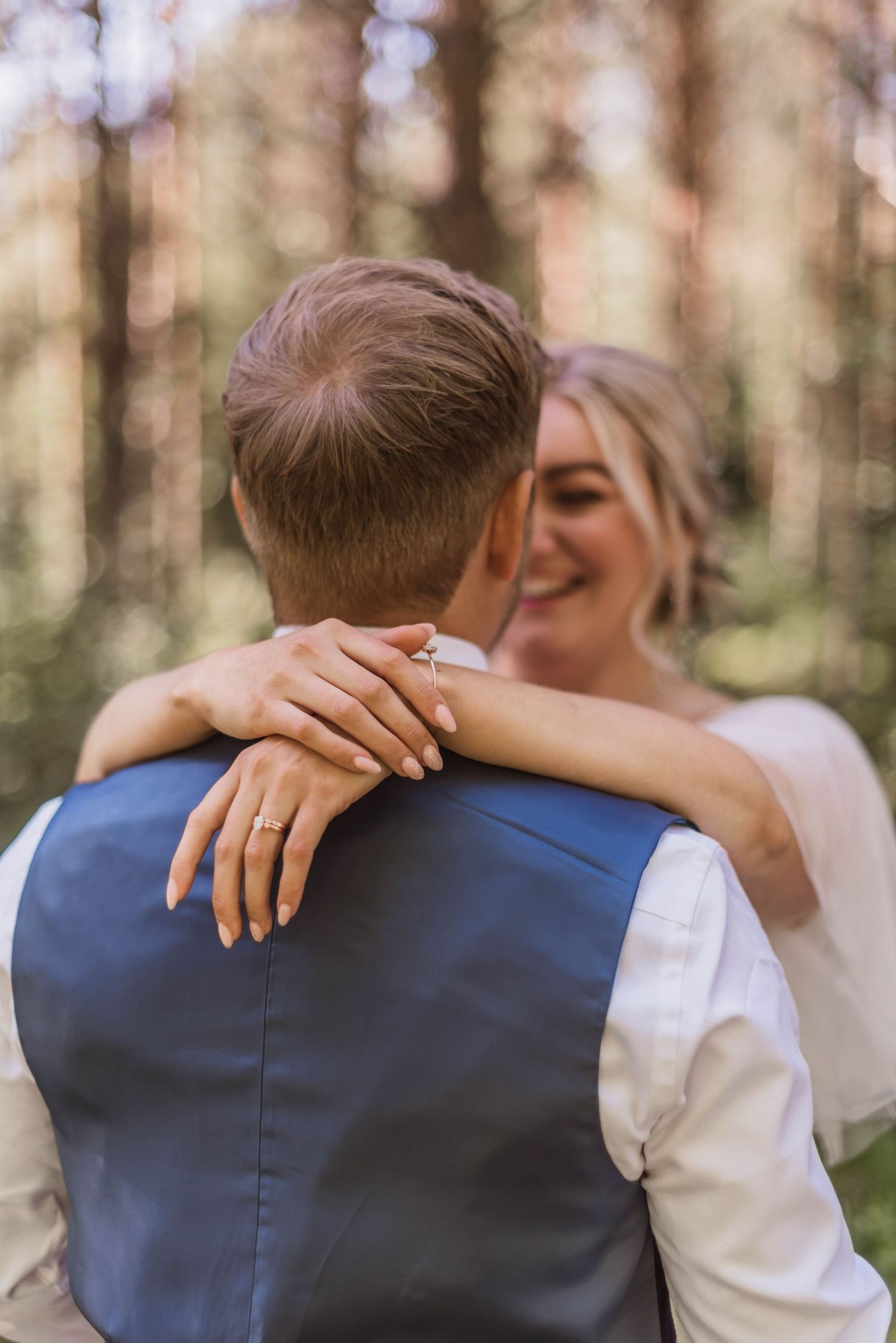 Romantic silhouette shots of a couple embracing in a sunlit forest wearing formal wedding attire.