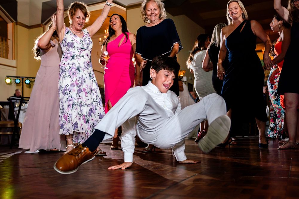 Wedding guests dancing low to the ground during a fun reception dance moment.