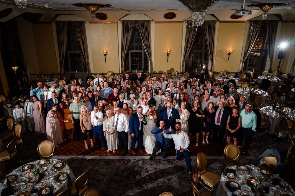 Large group photo of wedding guests gathered in the reception ballroom.
