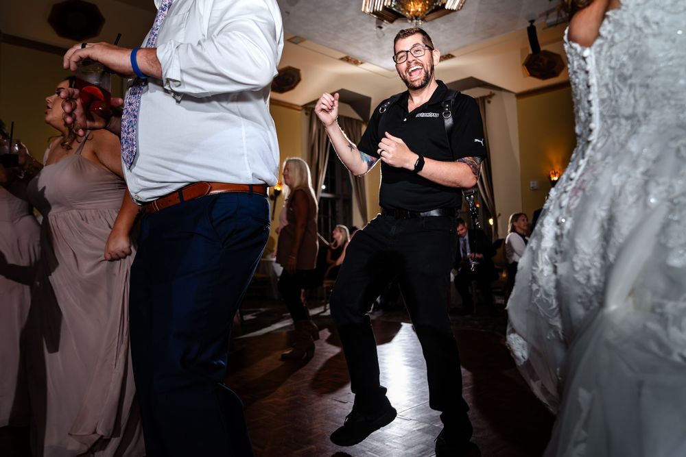 Wedding guests dancing and celebrating on a dimly lit dance floor.