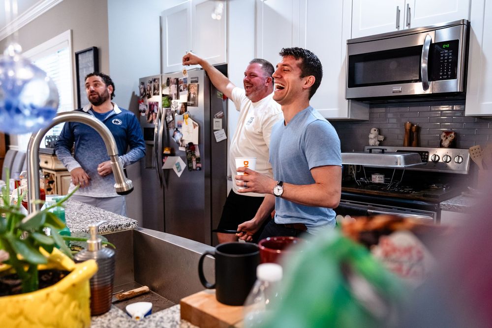 Modern kitchen gathering with people socializing and preparing food.
