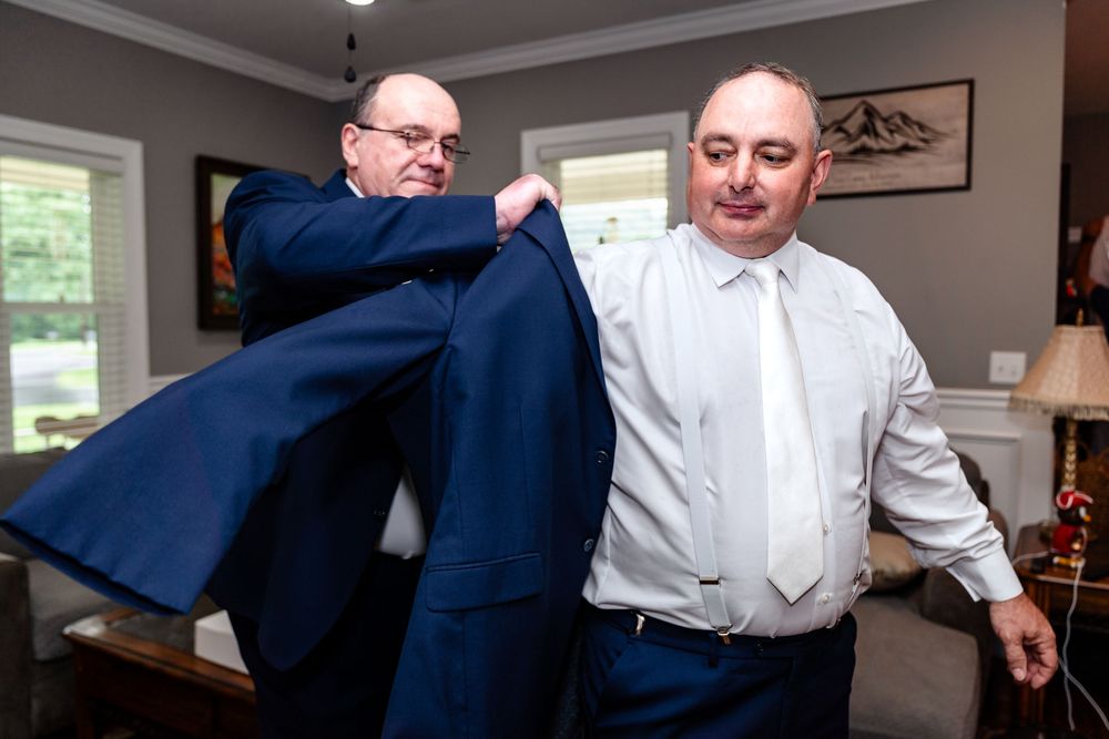 Wedding party members in suits and formal wear interacting in an indoor setting.