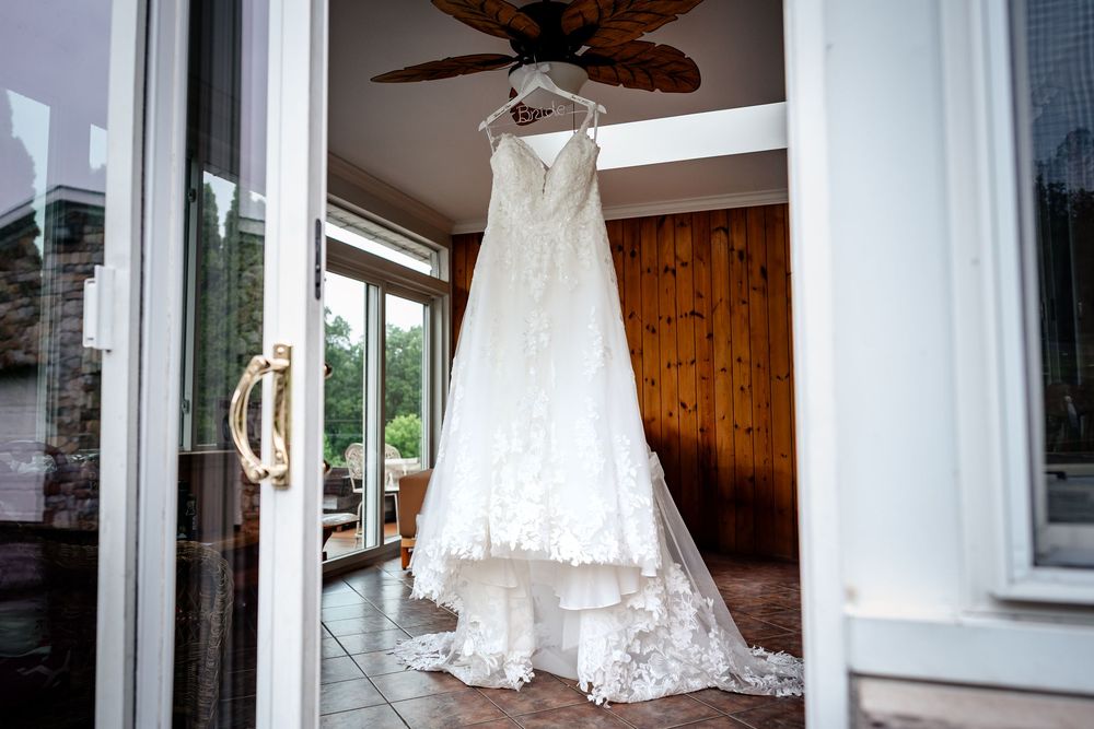 White wedding dress hanging in window with natural light streaming in.