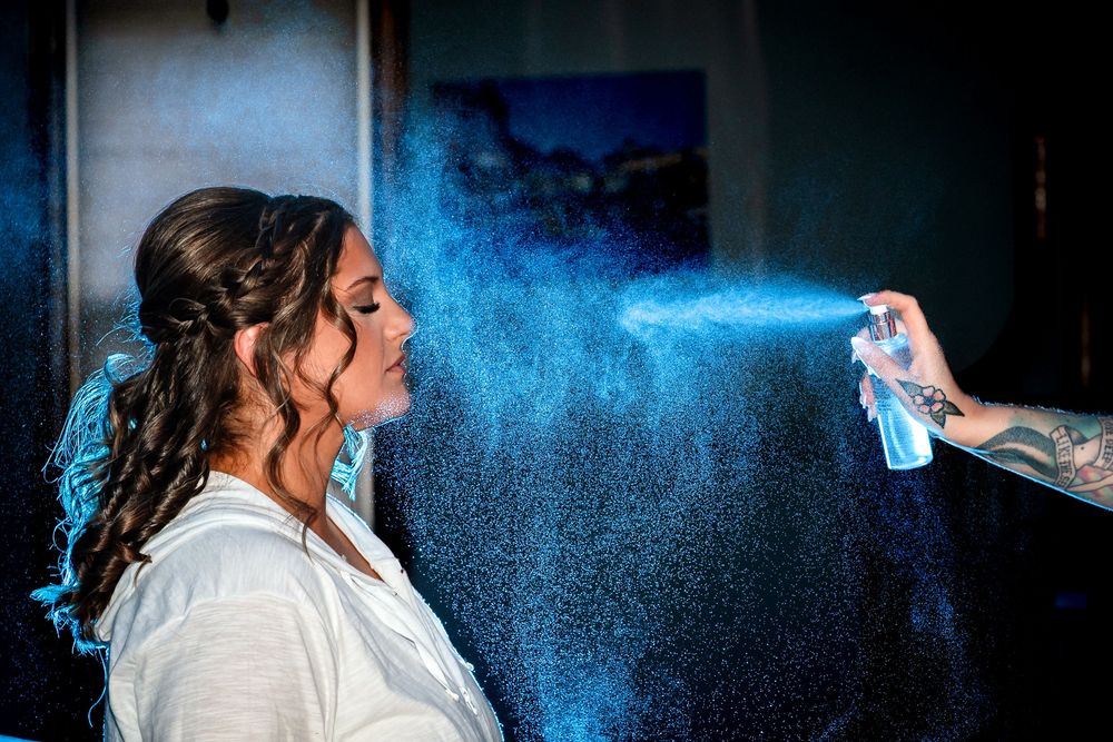 Blue hairspray being applied in a dark room with dramatic lighting effects.
