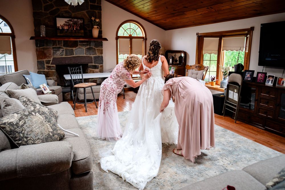 Wedding preparation scene in a rustic room with stone walls and wooden ceiling.
