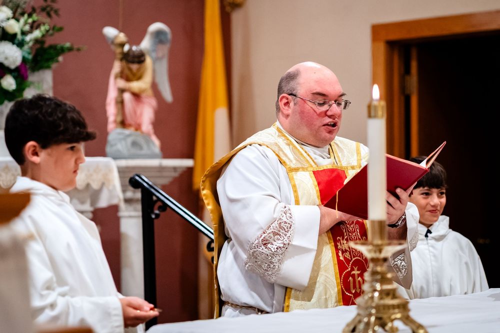 Altar servers in white robes assist during a Catholic mass ceremony.