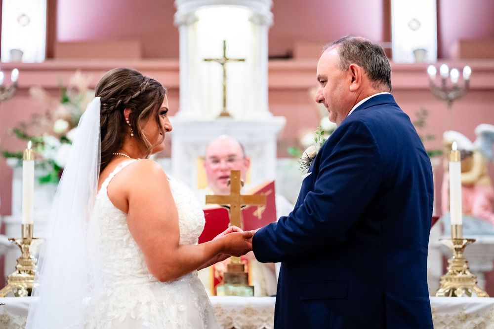Wedding ceremony moments captured in a Catholic church with pink walls and white columns.