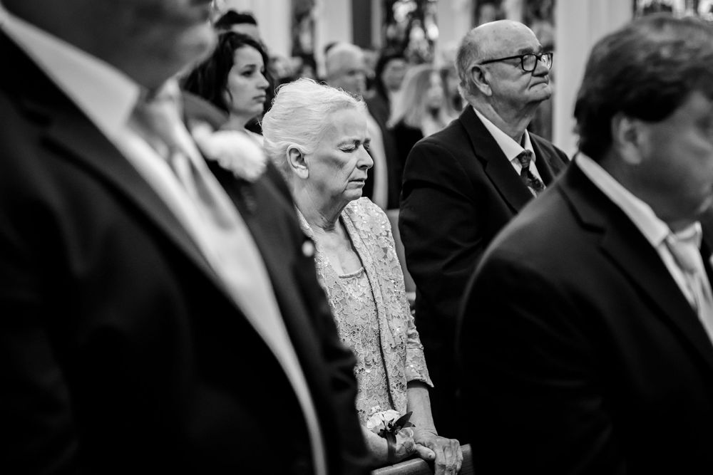 Wedding guests seated in church pews during ceremony in black and white.