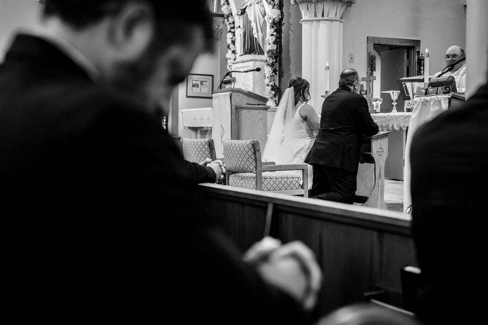Black and white photo of wedding ceremony attendees in church pews.