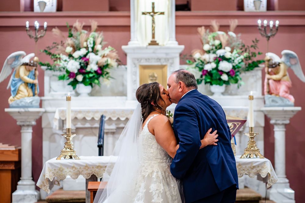 Wedding ceremony moments in Catholic church with pink walls and decorative altar.