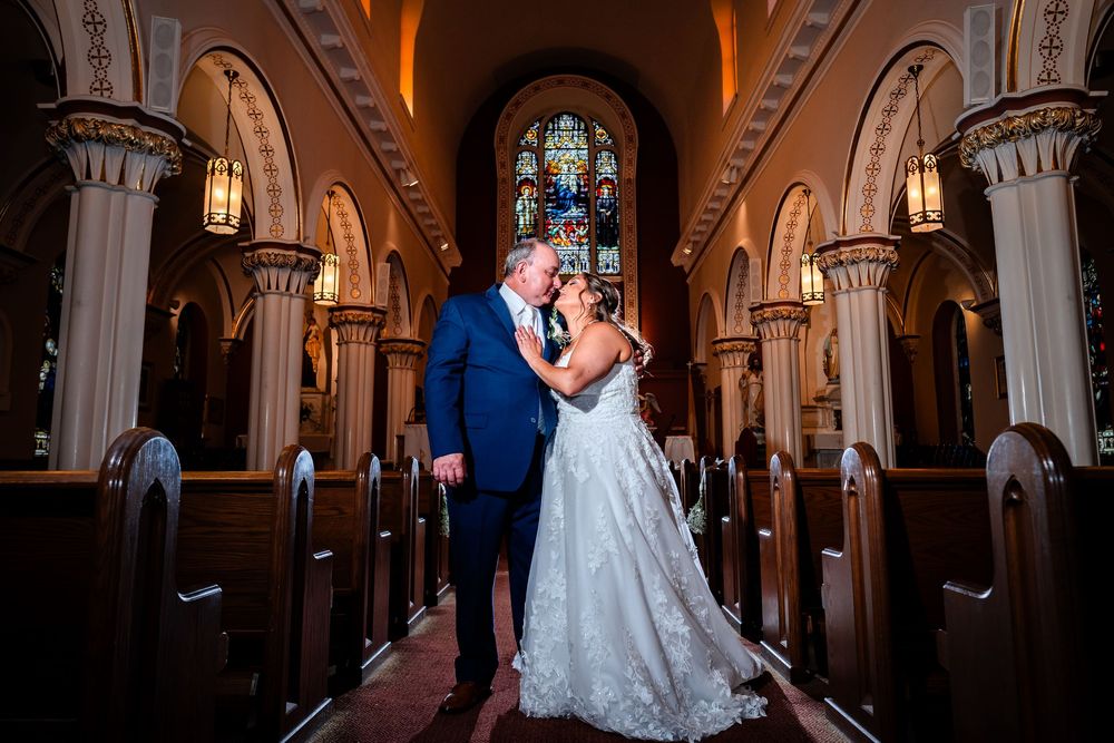 Interior of historic church with dramatic lighting and gothic architectural details during wedding ceremony.