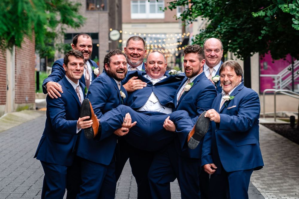 Groomsmen in navy suits posing together outdoors for fun group photo.