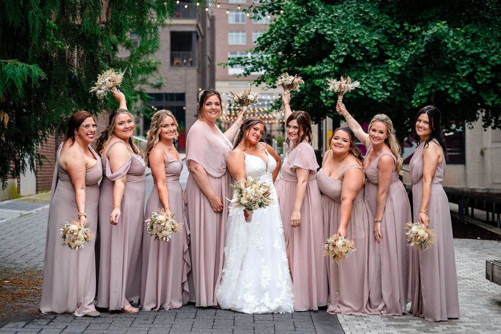 Wedding party in blush pink bridesmaid dresses posing outdoors.