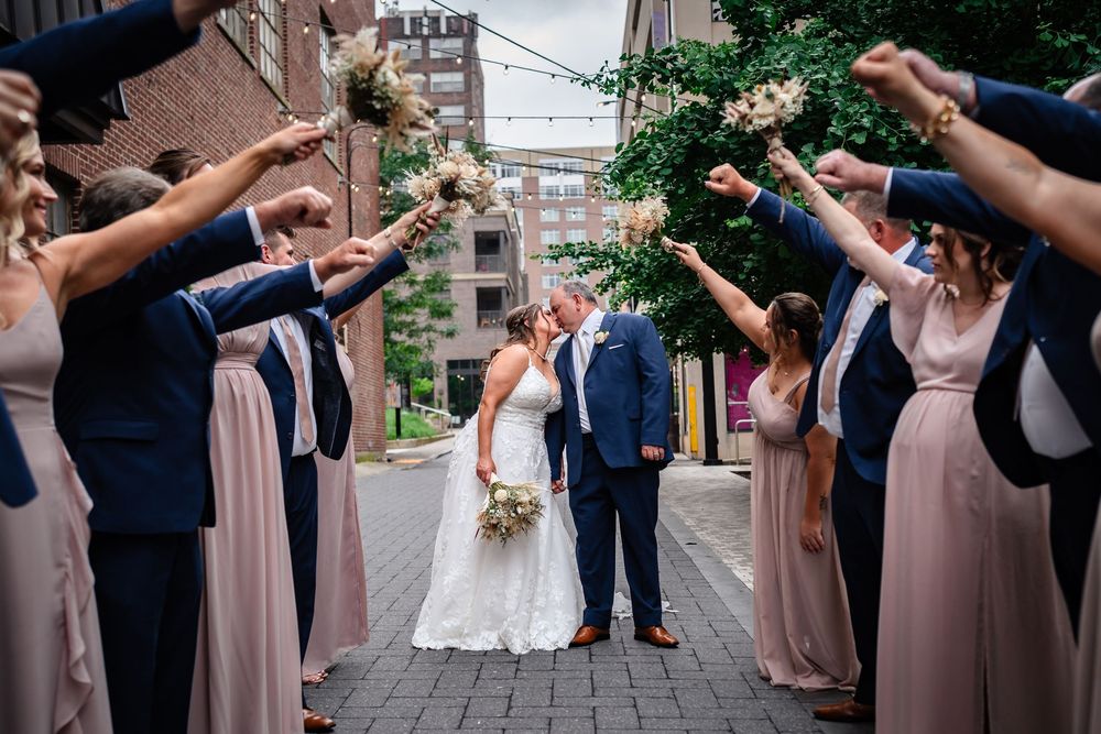 Wedding celebration with bridal party in pink dresses on urban street.