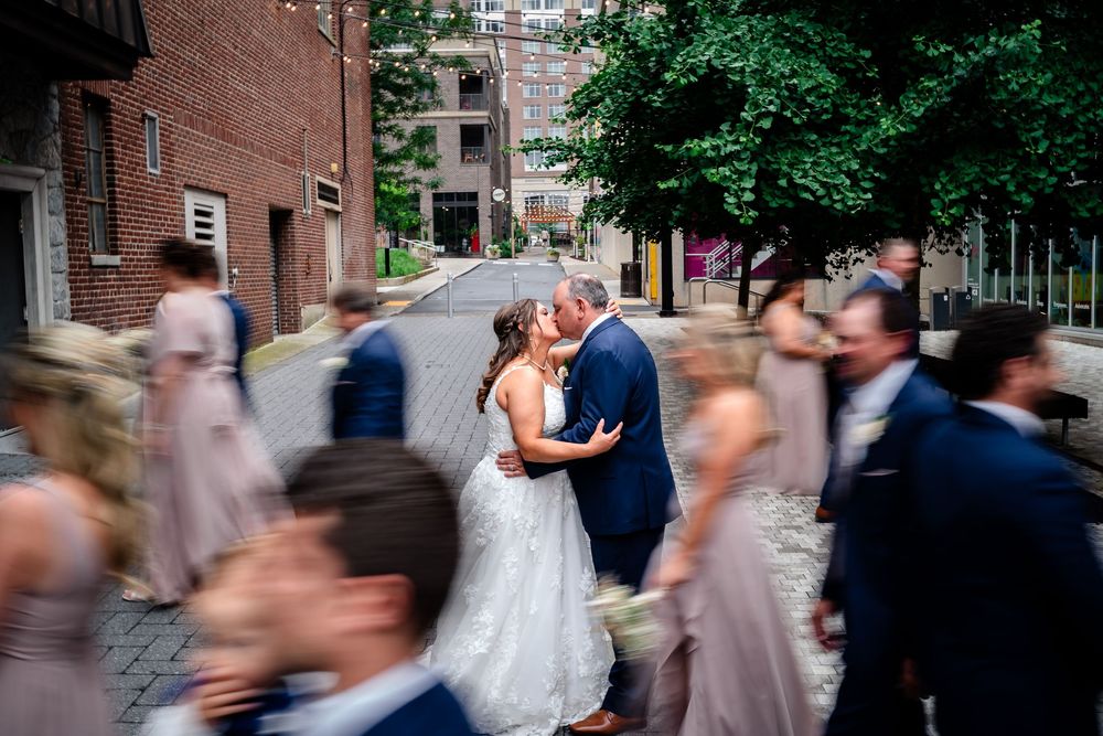 Wedding party processional on cobblestone street with motion blur effect.