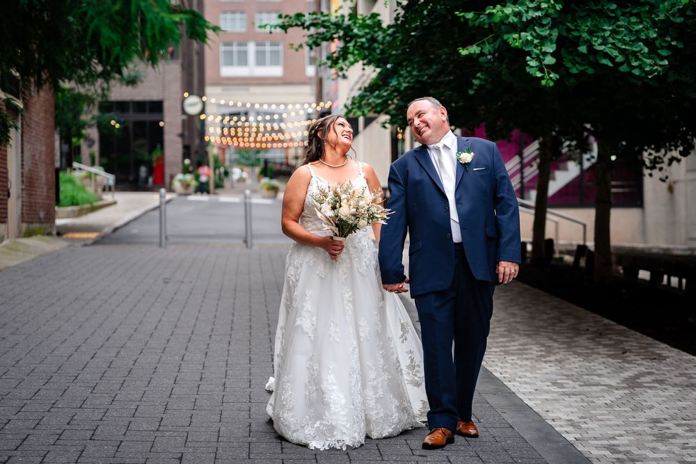 Newlyweds walking with bridal party on historic cobblestone street.