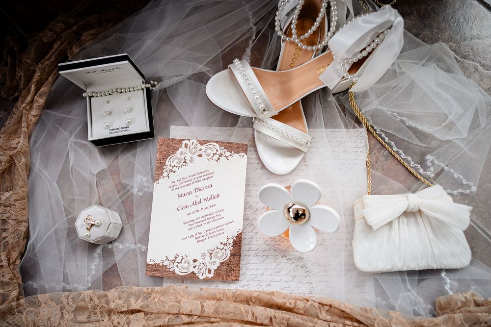 Wedding dress and accessories laid out with invitation details.