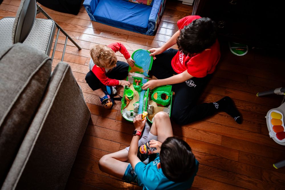 Children playing with colorful toys on hardwood floor during wedding festivities.