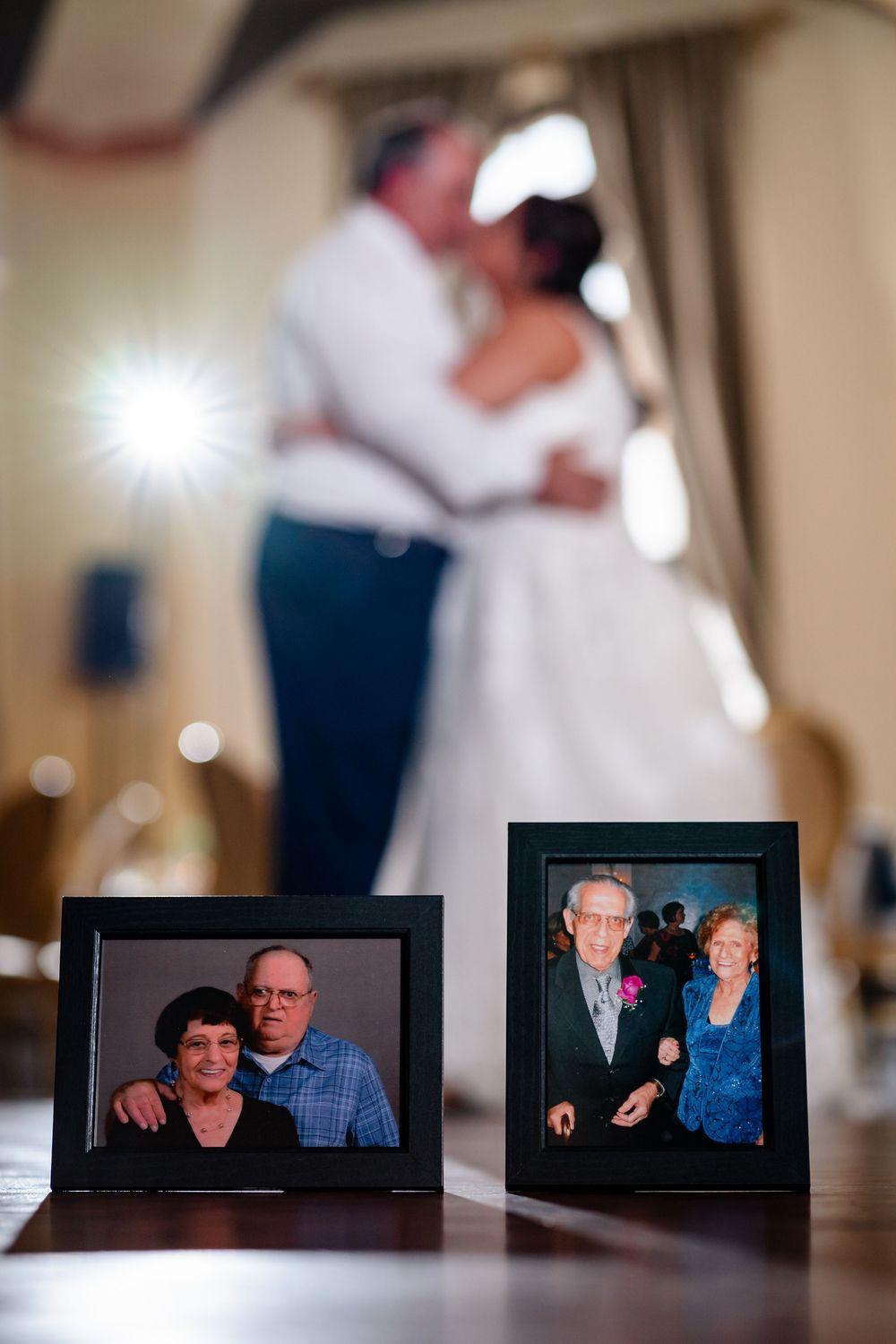 Row of framed family photos displayed on wooden table at wedding reception.