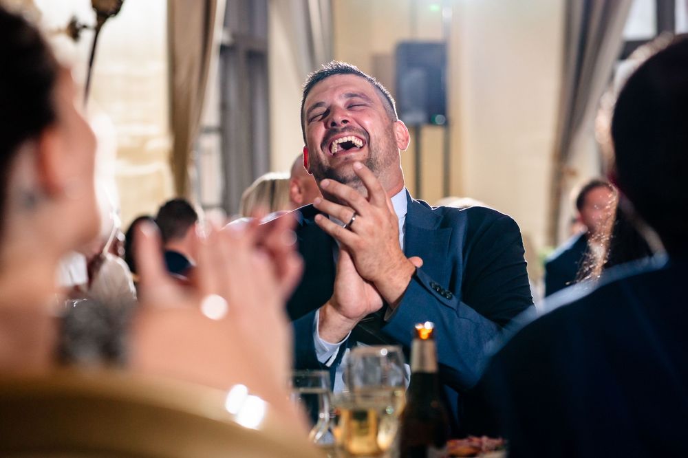 Wedding guests react with laughter during reception speeches.