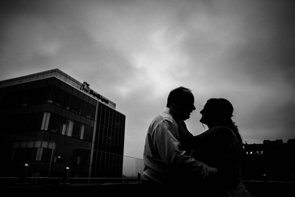 Dramatic silhouettes against evening sky at outdoor wedding venue.