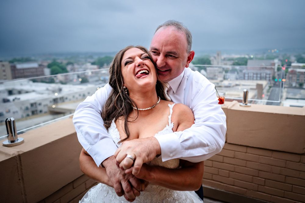 Couple shares intimate moment on rooftop with cityscape backdrop.
