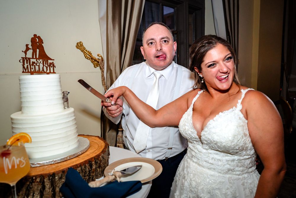 Wedding cake cutting ceremony with white tiered cake at reception.